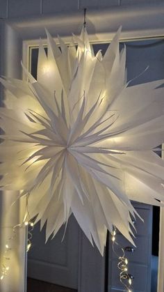 a large white paper snowflake hanging from the ceiling in front of a mirror