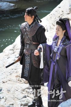 two people dressed in costumes walking on rocks