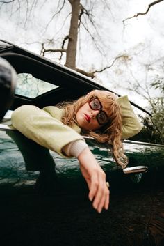 a woman leaning out the window of a green car