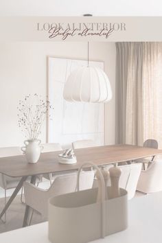 a dining room table with white chairs and a vase on the table next to it