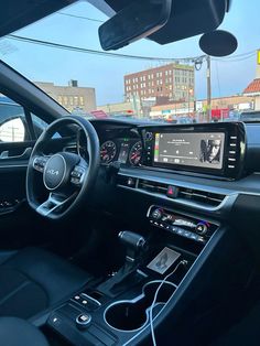 the interior of a car with an entertainment system and steering wheel controls in front of it