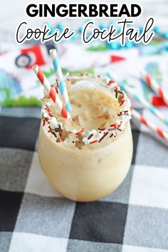 an iced drink with sprinkles and candy canes on the top is sitting on a checkered tablecloth