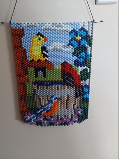 a beaded wall hanging with an image of birds in the sky and other animals on it