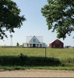 a red and white house sitting on top of a lush green field