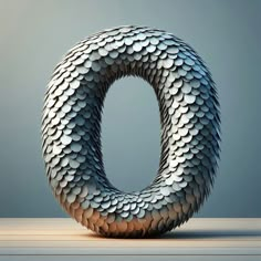 the letter o is made out of silver scales and sits on top of a wooden table