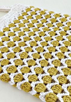 a crocheted yellow and white bag sitting on top of a table next to a pair of scissors