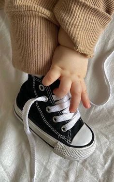 a small child's hand holding onto a pair of black and white shoes