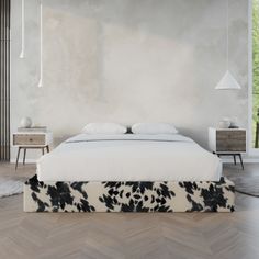 a white bed with black and white pillows on top of it in a room next to two nightstands