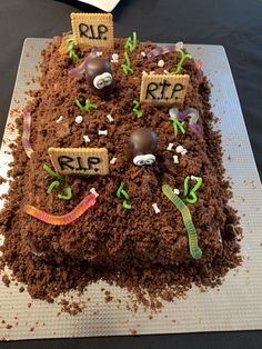 a cake made to look like dirt with the words rip spelled on it and worms crawling around