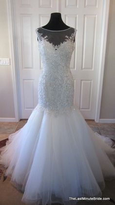 a white wedding dress on display in front of a door with a black mannequin