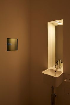 a bathroom sink sitting under a mirror next to a wall mounted soap dispenser