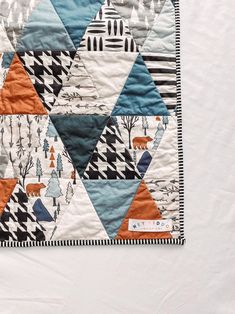 a quilted wall hanging with an orange, blue and white triangle design on it