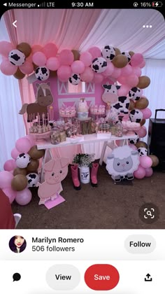 the table is set up with pink and brown balloons, cow decorations, and farm animals