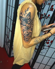 a woman with a butterfly tattoo on her arm holding a cell phone and looking at it