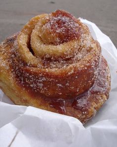 a cinnamon roll sitting on top of a piece of wax paper covered in powdered sugar