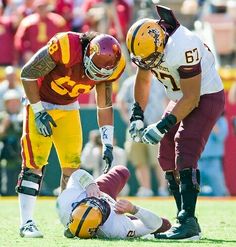 two football players are on the field with one laying on the ground and another standing