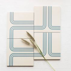 two square tiles with blue lines and a single flower on the left, against a white background