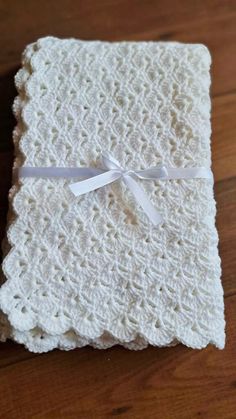 a white crocheted blanket on top of a wooden table