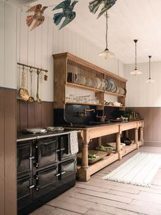 an old fashioned kitchen with wooden cabinets and black stove top oven, hanging bird decorations on the wall