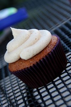 a cupcake with white frosting sitting on top of a grill