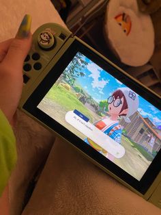 a person holding a nintendo wii game controller in front of a screen with an anime character on it