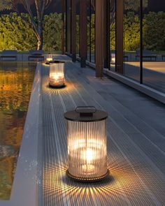 two lanterns sitting on the side of a building next to a body of water with trees in the background