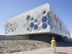 a person walking in front of a building with hexagonal windows on the side