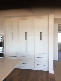 an empty kitchen with white cabinets and wood floors