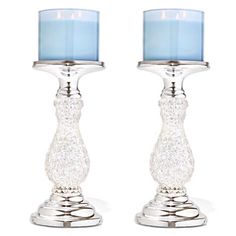 two clear glass candlesticks sitting next to each other