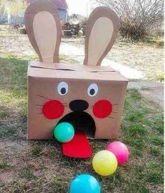 a cardboard box that has some balloons in front of it and an animal face on top