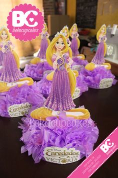 some little princess figurines sitting on top of purple tissue pom poms