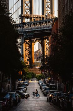 a person riding a bike down a city street under a bridge with cars parked on both sides