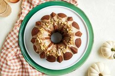 a bundt cake sitting on top of a white plate next to two pumpkins