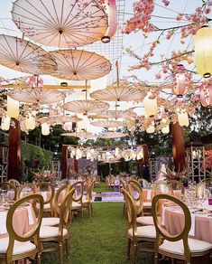 an outdoor dining area with tables and umbrellas hanging from the ceiling over it's grass