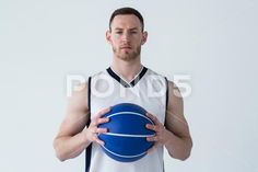 a basketball player holding a blue ball in his hands and looking up at the camera