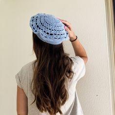 a woman standing in front of a mirror wearing a blue crochet hat