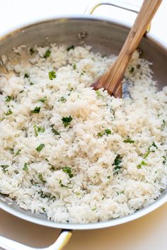 rice is being cooked in a pan with a wooden spoon