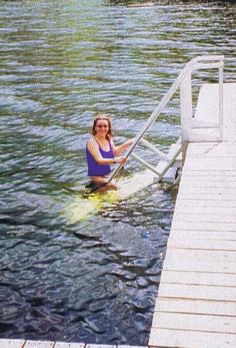 a woman standing in the water next to a dock with a life guard on it