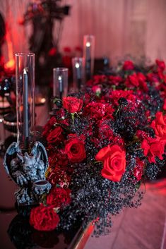 a table topped with red flowers and candles