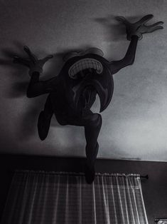 a black and white photo of a cartoon character hanging from the ceiling