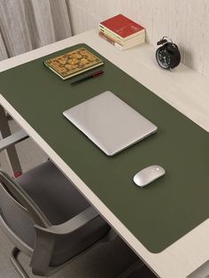 a laptop computer sitting on top of a green table next to a mouse pad and alarm clock