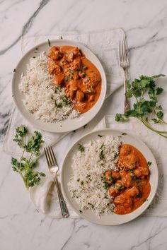 two plates filled with rice and meat on top of a white table cloth next to silverware