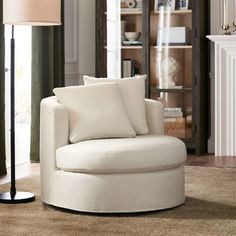 a white chair sitting on top of a rug in a living room next to a lamp