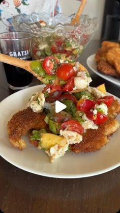 fried chicken with tomatoes, lettuce and other toppings on a white plate