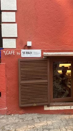 an open window on the side of a red building with a sign above it that says cafe by sukio