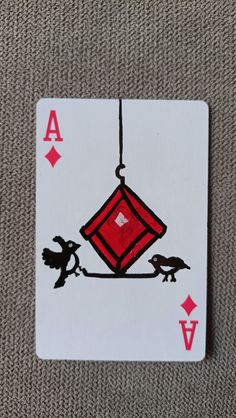 an ace playing card with red and black designs on it's sides, hanging from a string