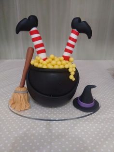 a witches caulder filled with yellow candy and topped with two brooms, sitting on top of a table