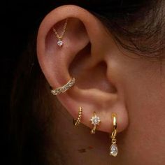 an ear with three different types of piercings on it's sides and one is gold