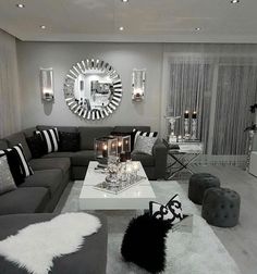 a living room filled with gray couches and white coffee table in front of a mirror