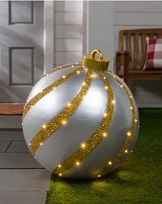 a white and gold christmas ornament sitting on top of a grass covered yard